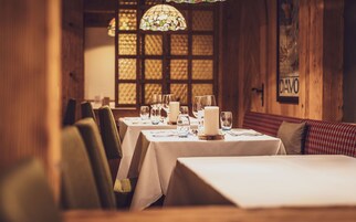 A restaurant interior with wooden walls, a stained glass window, and tables set for dining.