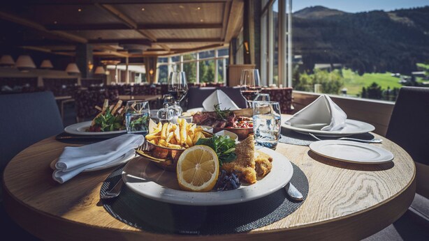A dining table with a meal, glasses, and a view of mountains. - Mountain Plaza Hotel (Davos)