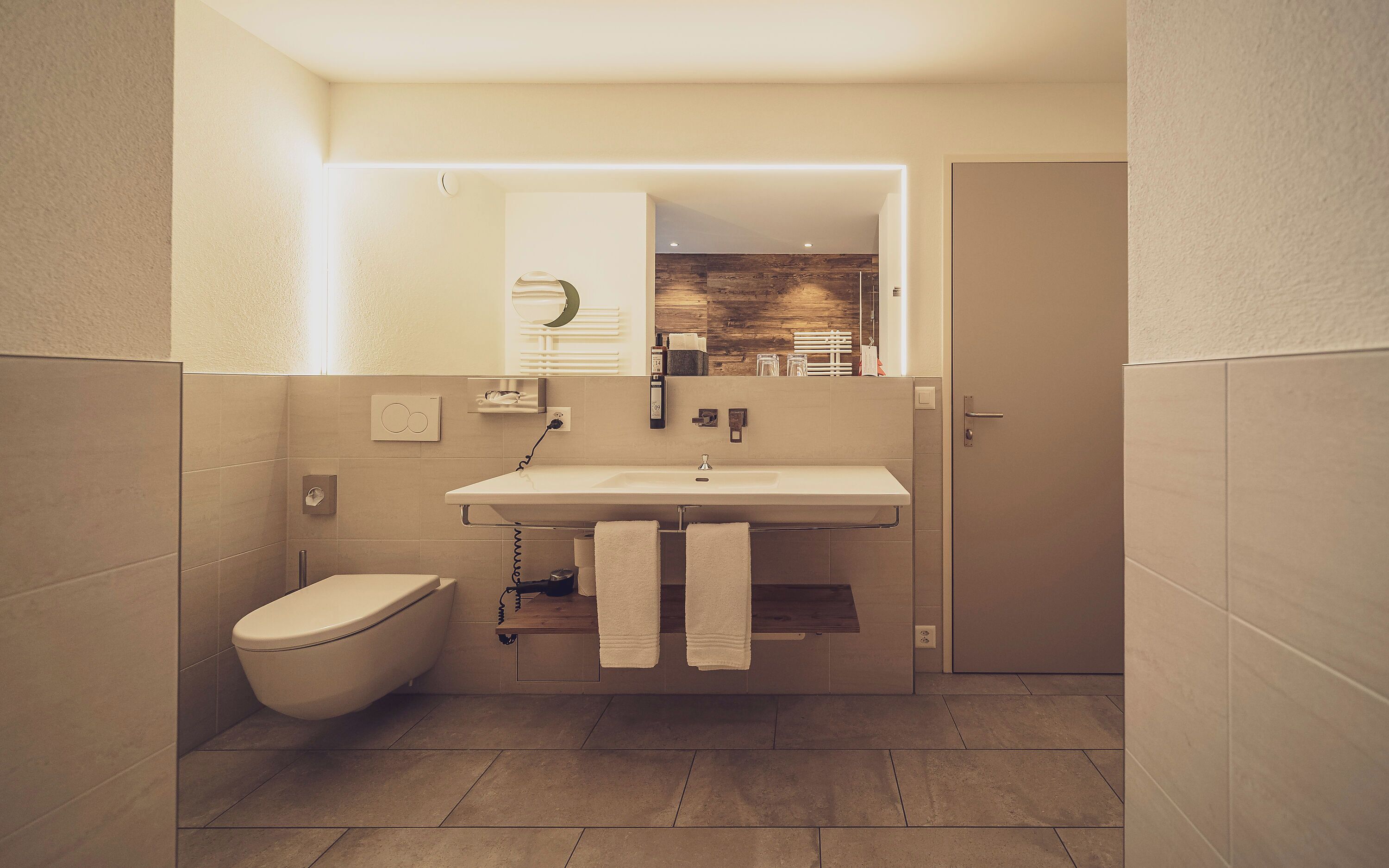 A modern bathroom with a toilet, sink, and towel rack.