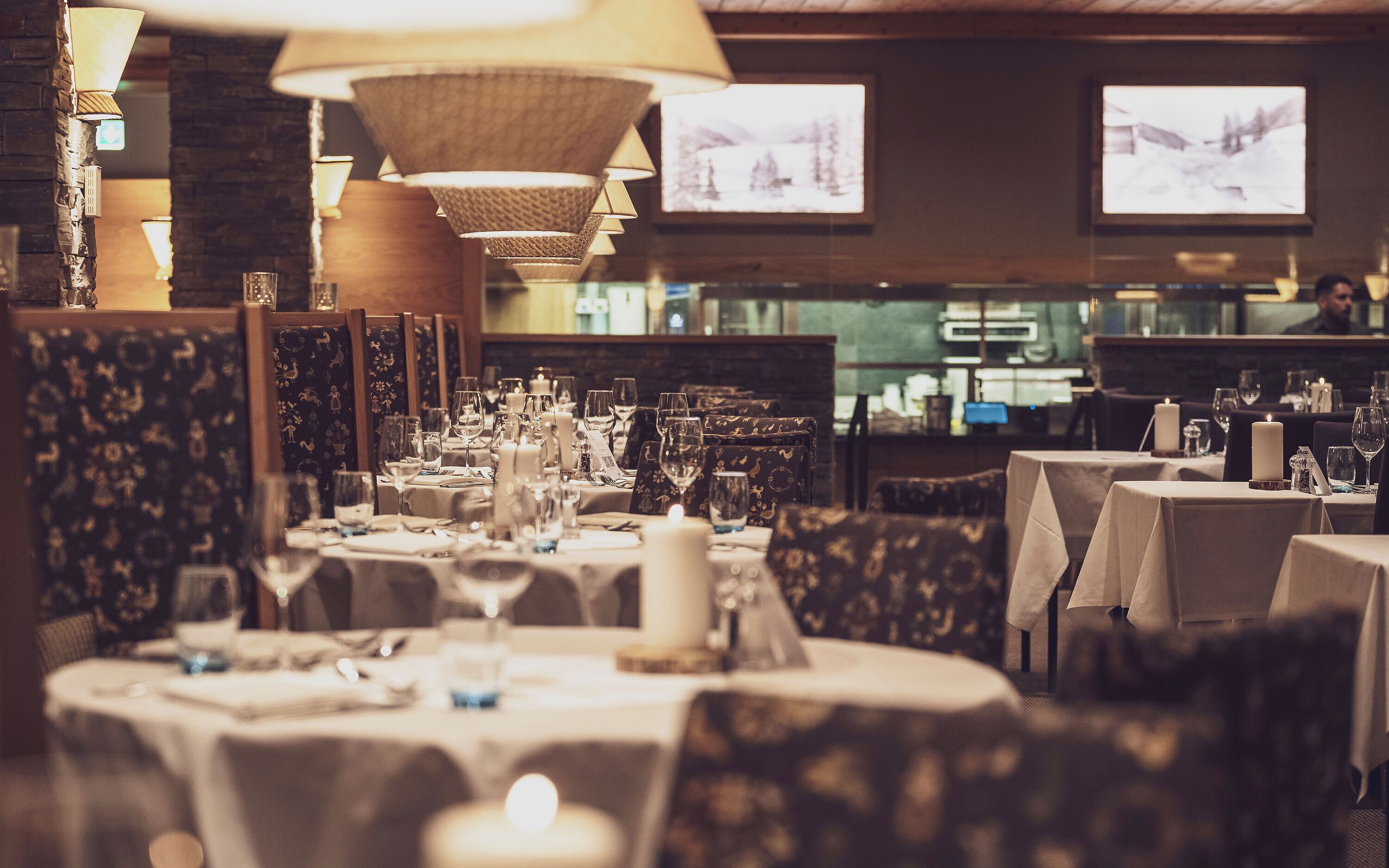 Ein Restaurant mit gedeckten Tischen, einer Bar und Fernsehern, die Bilder zeigen.