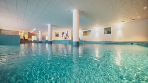 An indoor swimming pool with clear water, white pillars, and a tiled ceiling. - Mountain Plaza Hotel (Davos)