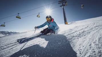A person skiing down a snowy slope with ski lifts in the background.