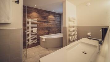Ein modernes Badezimmer mit einer freistehenden Badewanne, einer Wand mit Holzverkleidung und einer Duschkabine aus Glas.
