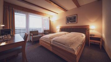 Ein Hotelzimmer mit Doppelbett, Schreibtisch mit Stuhl, einem kleinen Tisch und einer Lampe.