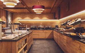 A buffet setup with various food items and beverages, wooden paneling, and a stone accent wall. - Mountain Plaza Hotel (Davos)