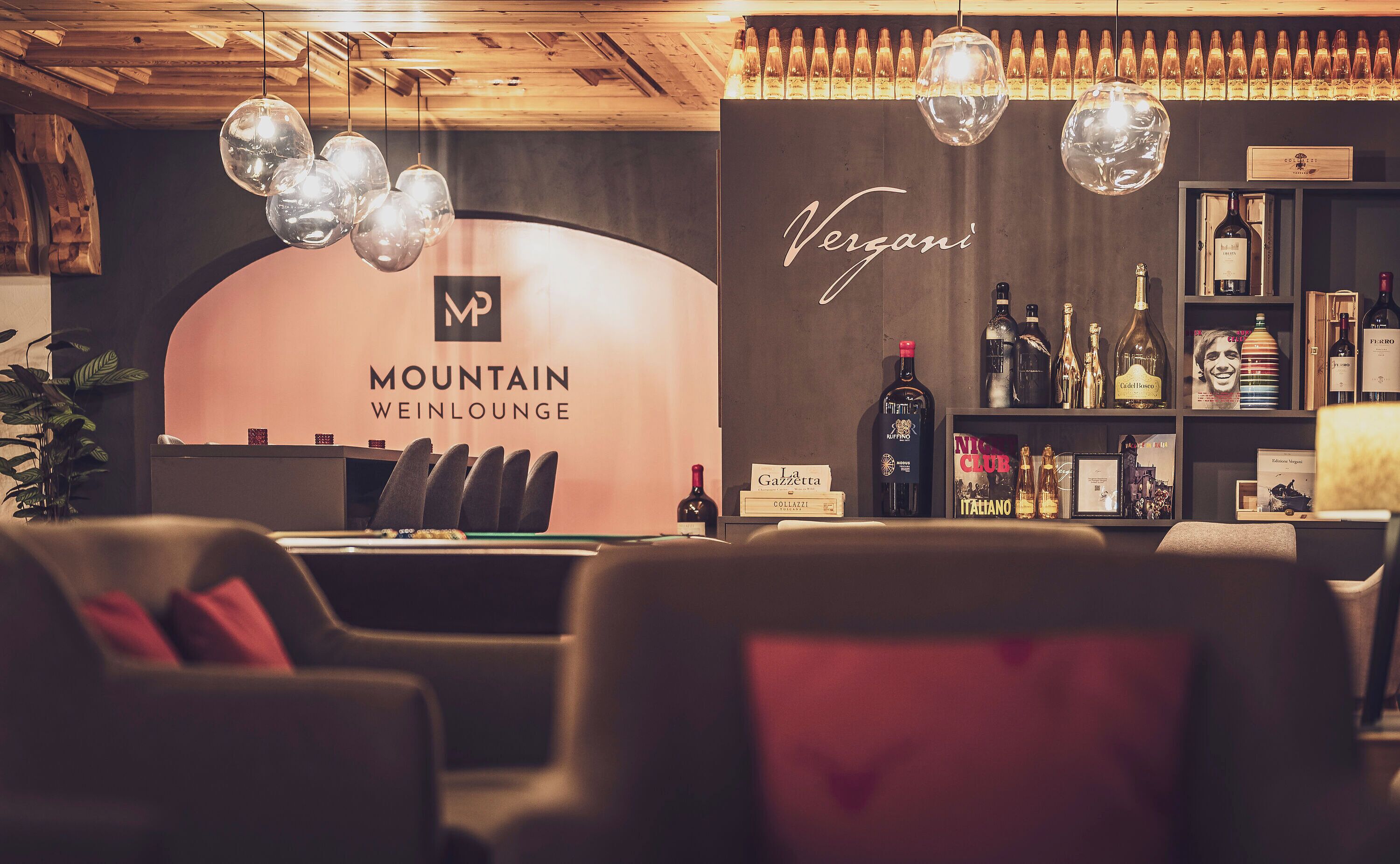 A lounge area with a bar, seating, and a wine display.
