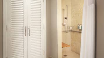 A bathroom with a walk-in shower, a toilet, and a white door with louvered panels.