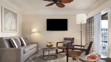 A modern living room with a grey sofa, a round coffee table, a wicker chair, and a ceiling fan.