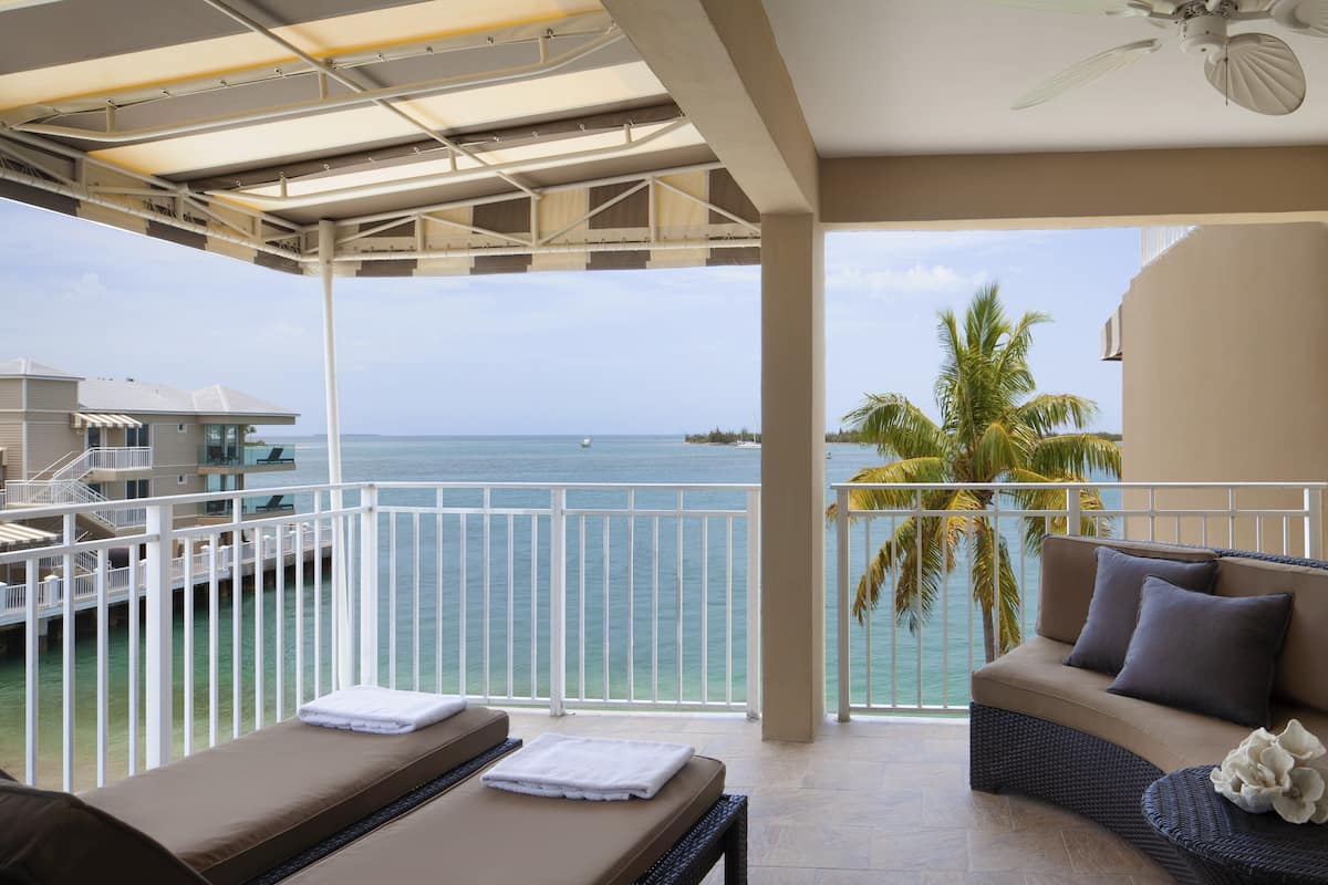 A balcony with a view of the ocean, a sofa, and a massage table.