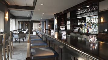 A bar area with a long counter, bar stools, and a well-stocked bar.
