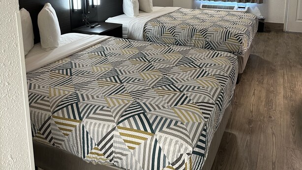 Una habitación de hotel con dos camas, cada una con ropa de cama estampada y cabeceros.