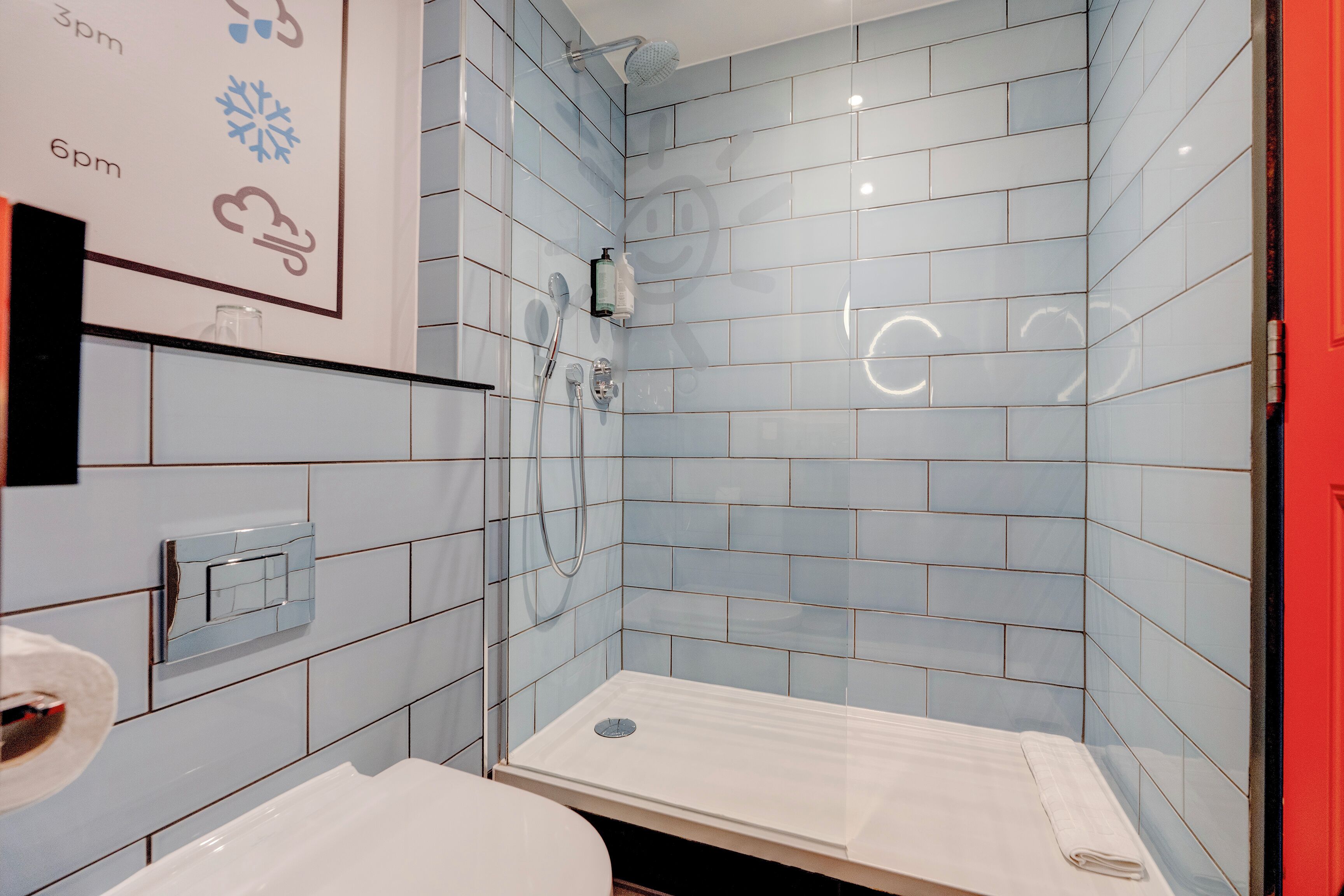 A bathroom with light blue tiles, a shower, a toilet, and a sink.