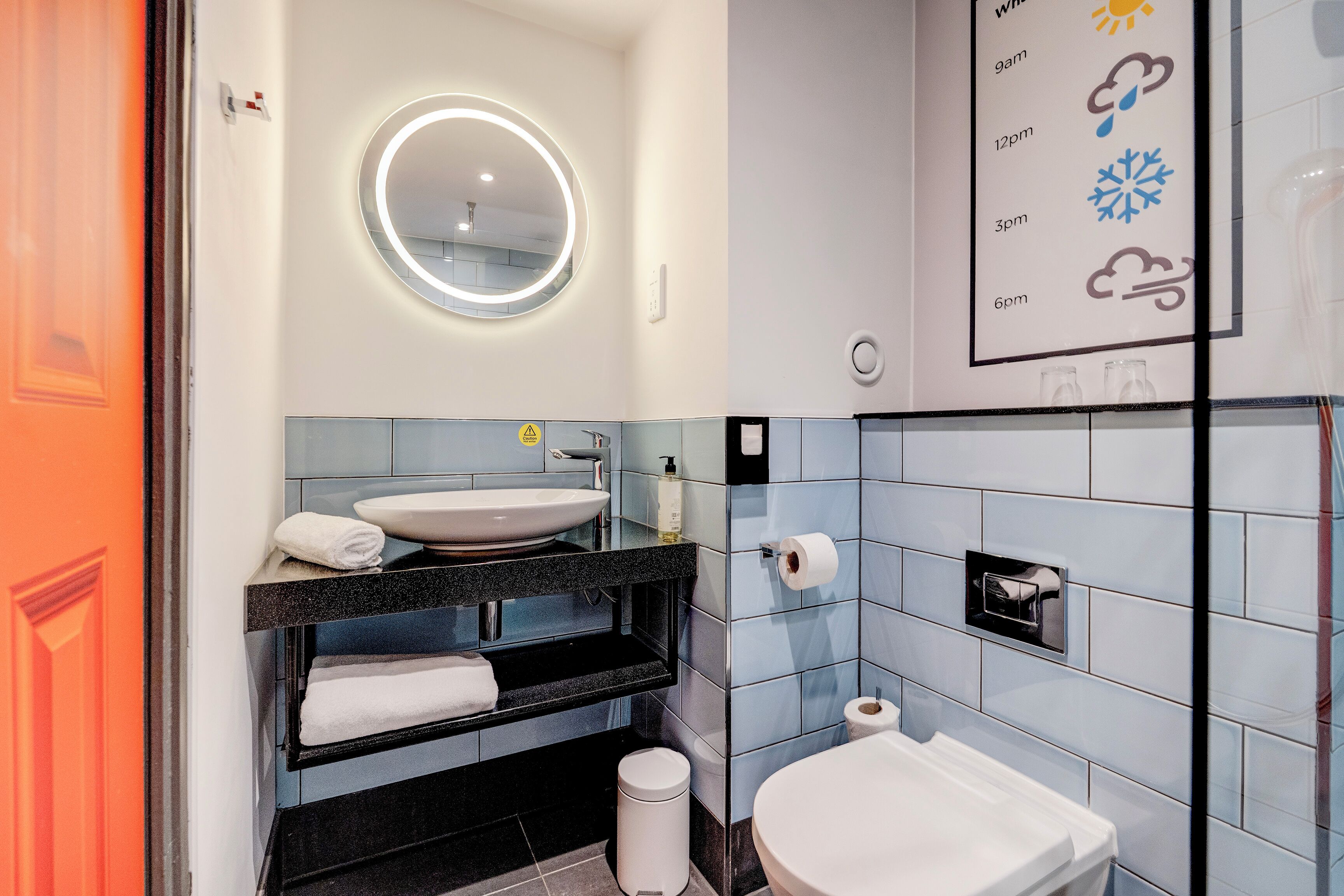 A modern bathroom with a round mirror, a sink, a toilet, and a shower area.