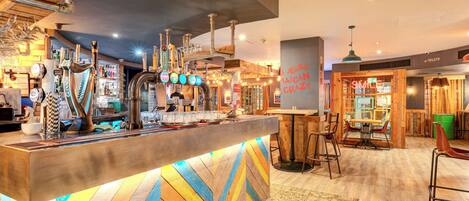 A bar area with a wooden counter, multiple taps, and a sign that reads "SMILE".