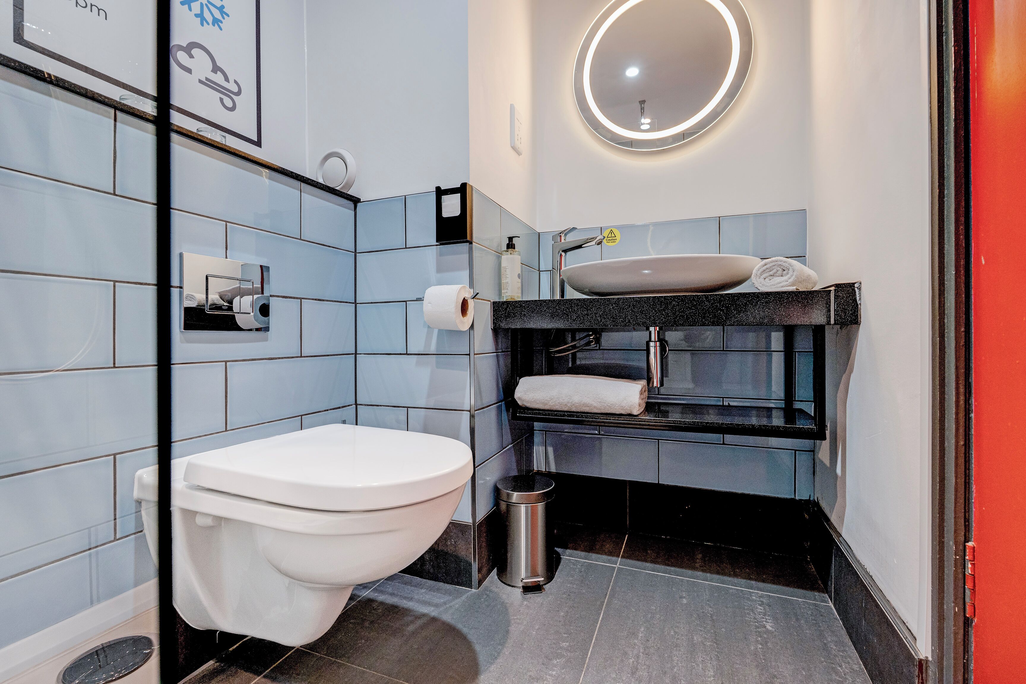 A modern bathroom with a toilet, sink, and mirror.