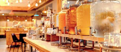 A bar area with multiple large glass jars filled with beverages, a coffee machine, and a wooden counter.