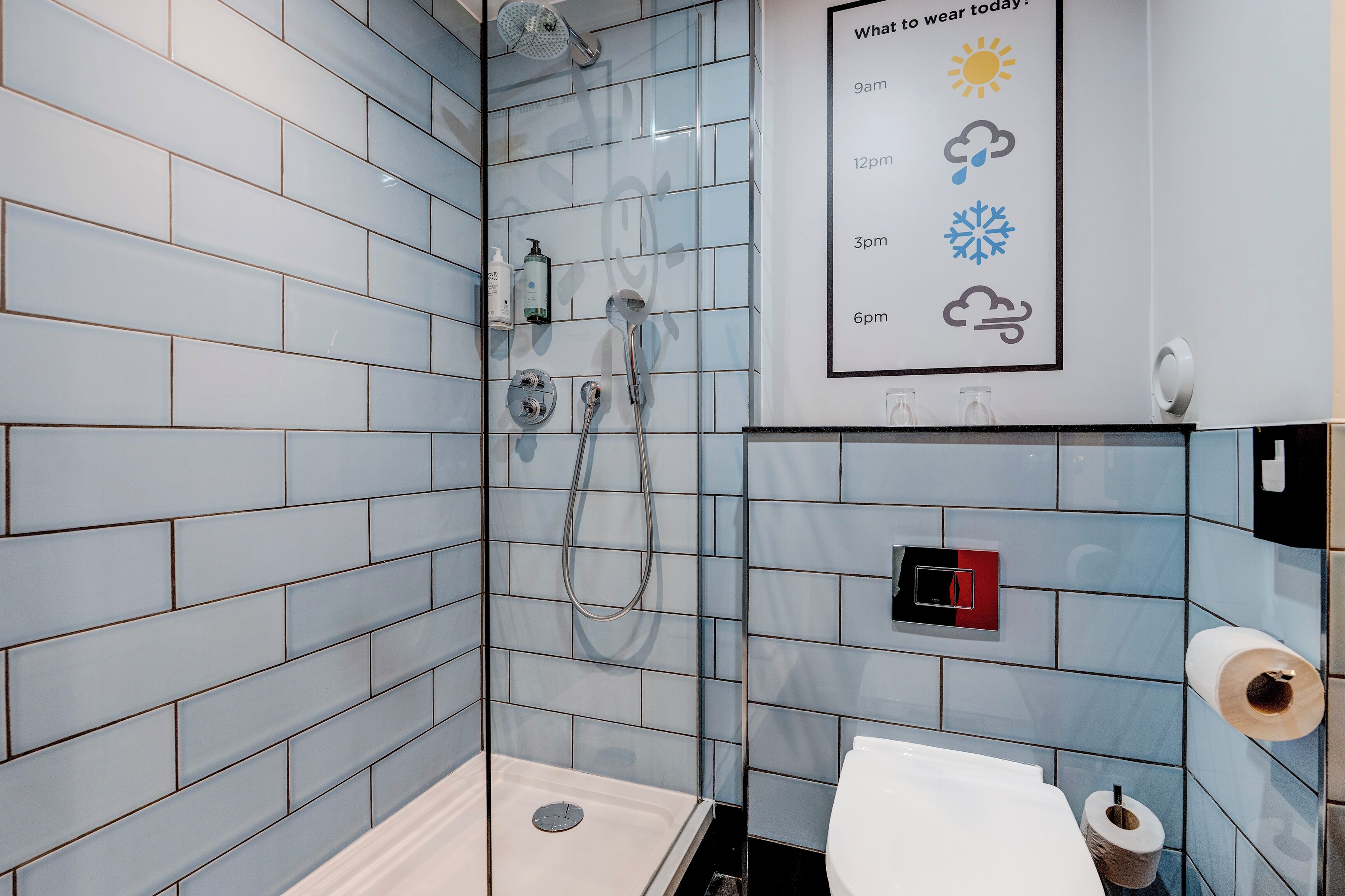A modern bathroom with a shower, toilet, and a wall-mounted sign indicating daily weather.