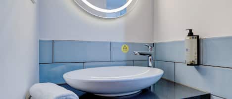 A modern bathroom with a round mirror, a white sink, and a towel on the counter.