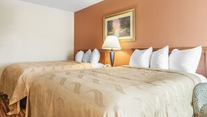 Una habitación de hotel con dos camas, una mesita de noche con lámpara y un cuadro en la pared.