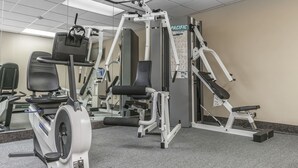 Un gimnasio con diversos equipos de ejercicio, que incluyen una bicicleta estática, una cinta de correr y máquinas de pesas.