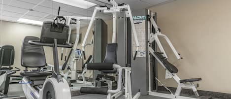 A gym with various exercise equipment, including a stationary bike, a treadmill, and weight machines.
