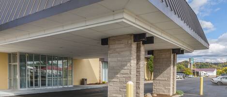 A modern building with a flat roof, large glass windows, and stone pillars.