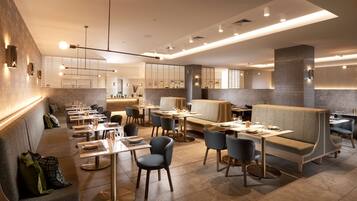 A modern restaurant interior with booths, tables, and a bar area.