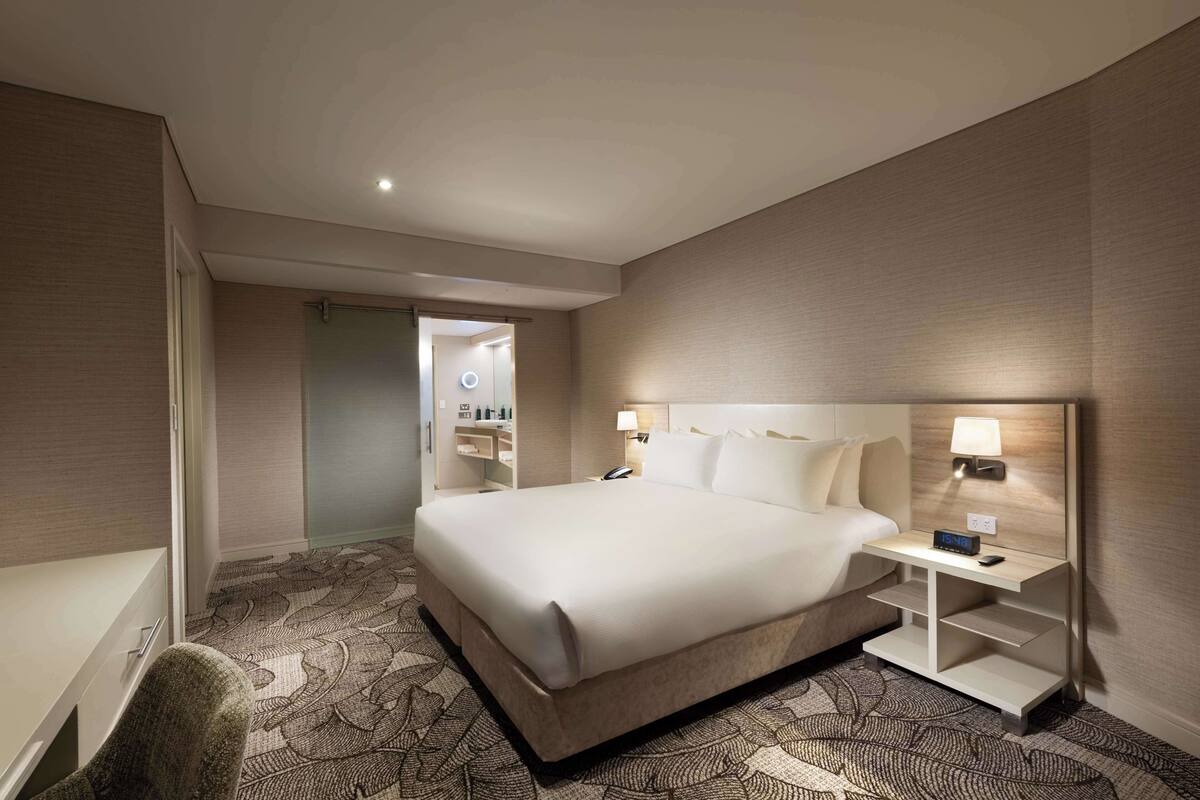 A hotel room with a large bed, bedside tables, a desk, and a chair.