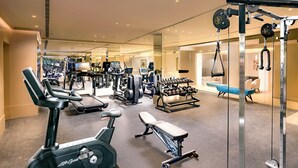 Un gimnasio con cintas de correr, elípticas, bancos de pesas y una jaula para sentadillas.