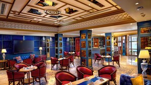 Un vestíbulo de hotel con zona de bar, espacios para sentarse y una pantalla grande.