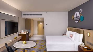 A hotel room with a bed, bedside table, TV, and a small round table with chairs.