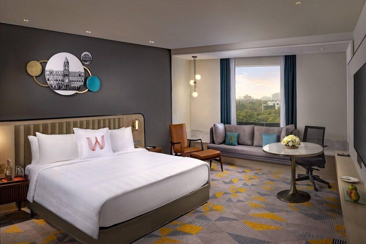 Une chambre d’hôtel avec un grand lit, un canapé, une petite table et une vue sur la ville.