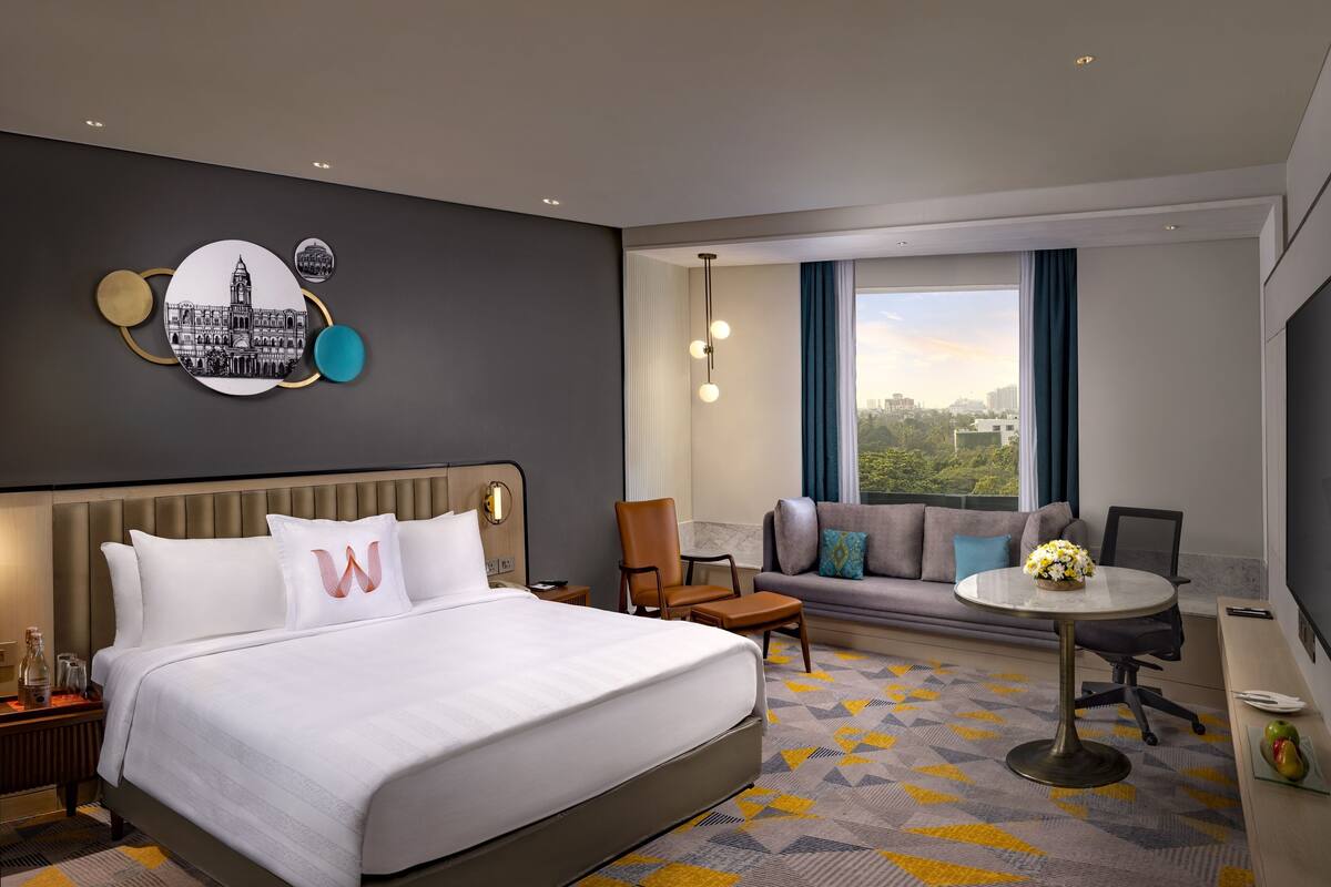 Une chambre d’hôtel avec un grand lit, un canapé, une petite table et une vue sur la ville.