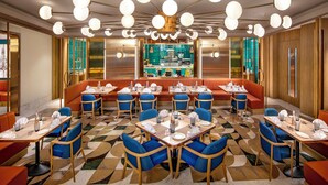 Un restaurante con mesas redondas, sillas azules y una zona de bar central.