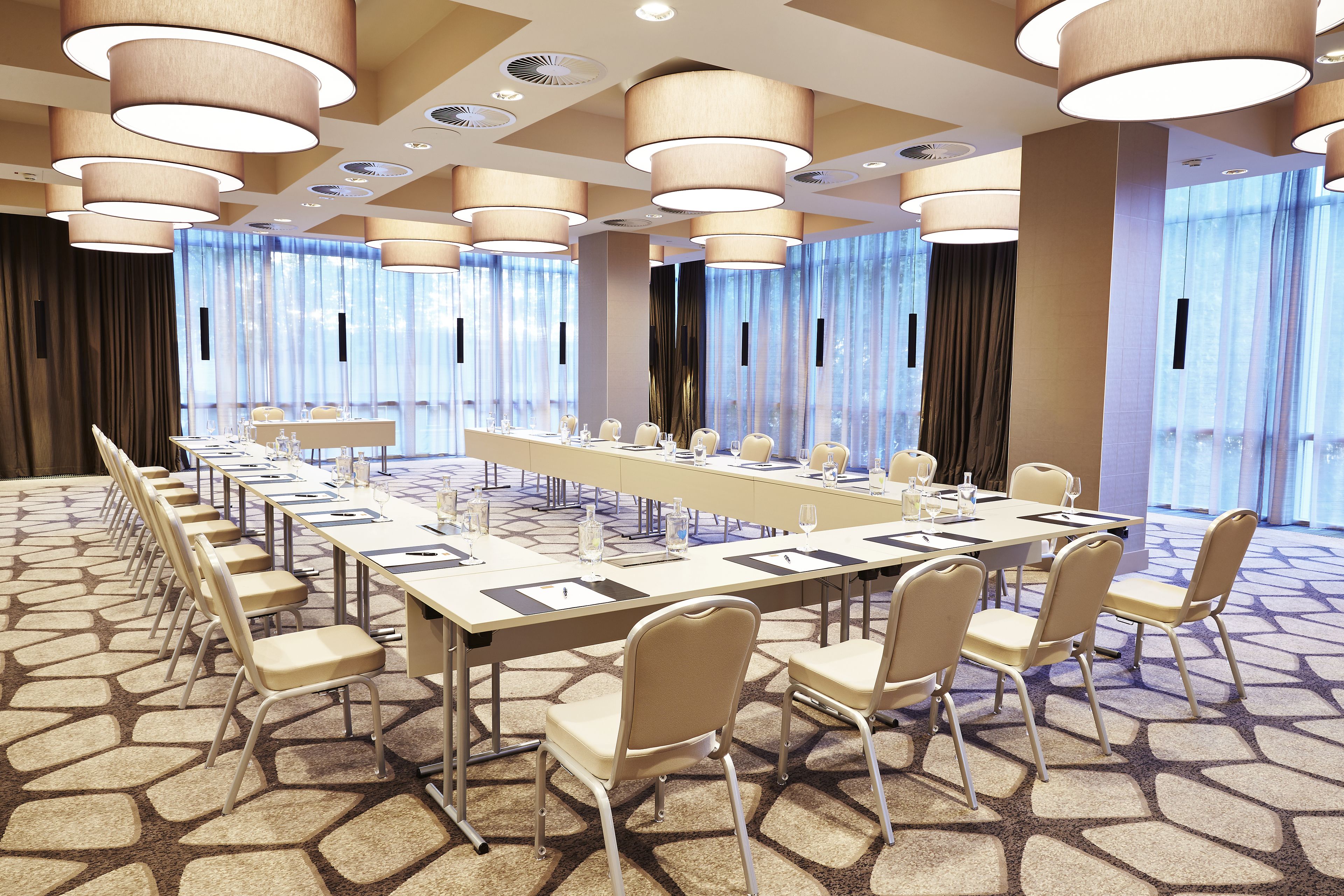 A conference room with a long table, chairs, and large windows with curtains.