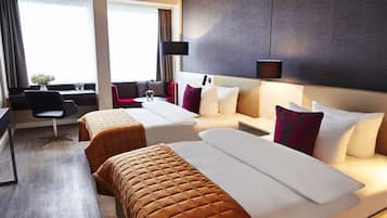 A hotel room with two beds, a desk, a chair, and a window with curtains.