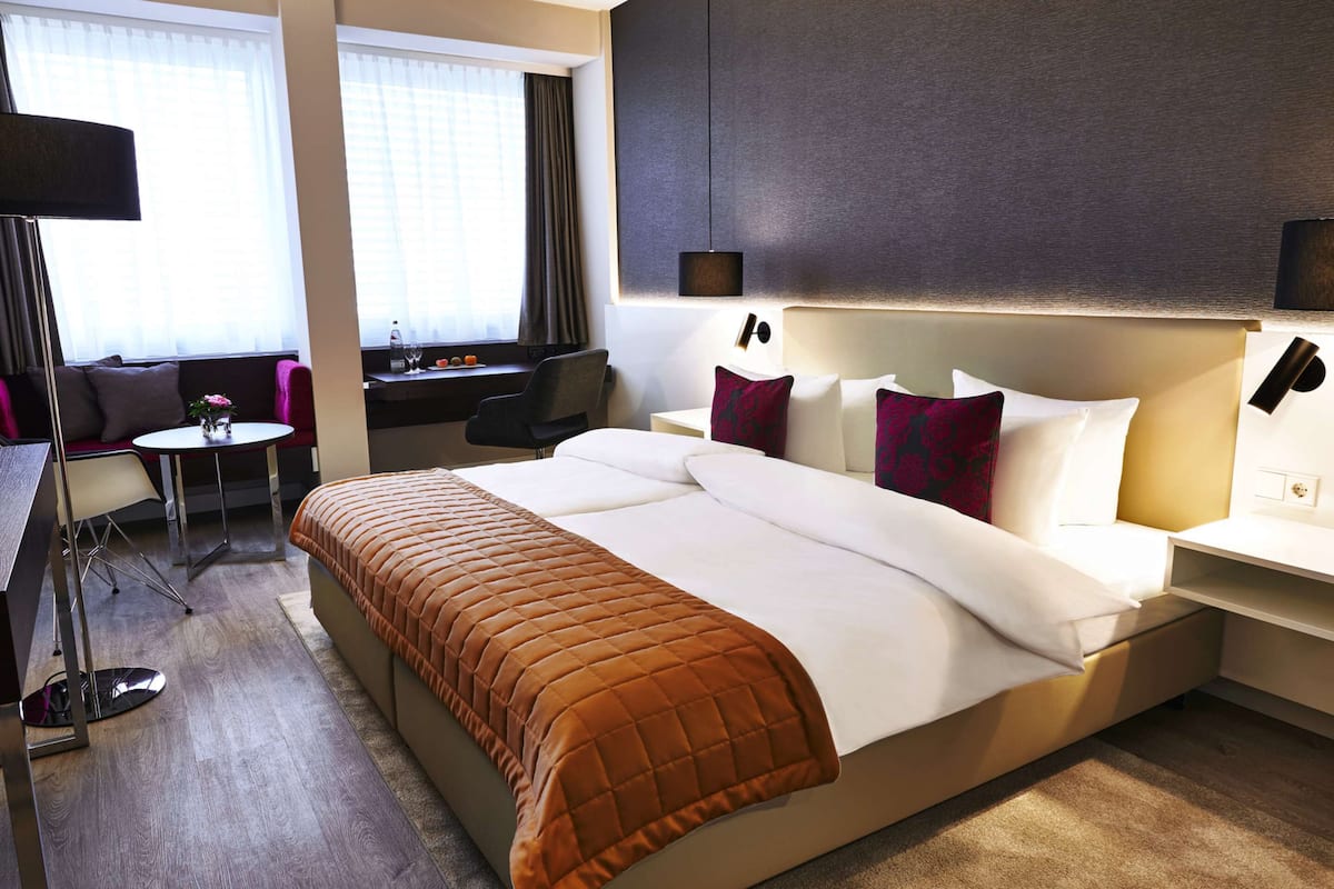 Una habitación de hotel con una cama grande, un escritorio, una silla y una mesita.