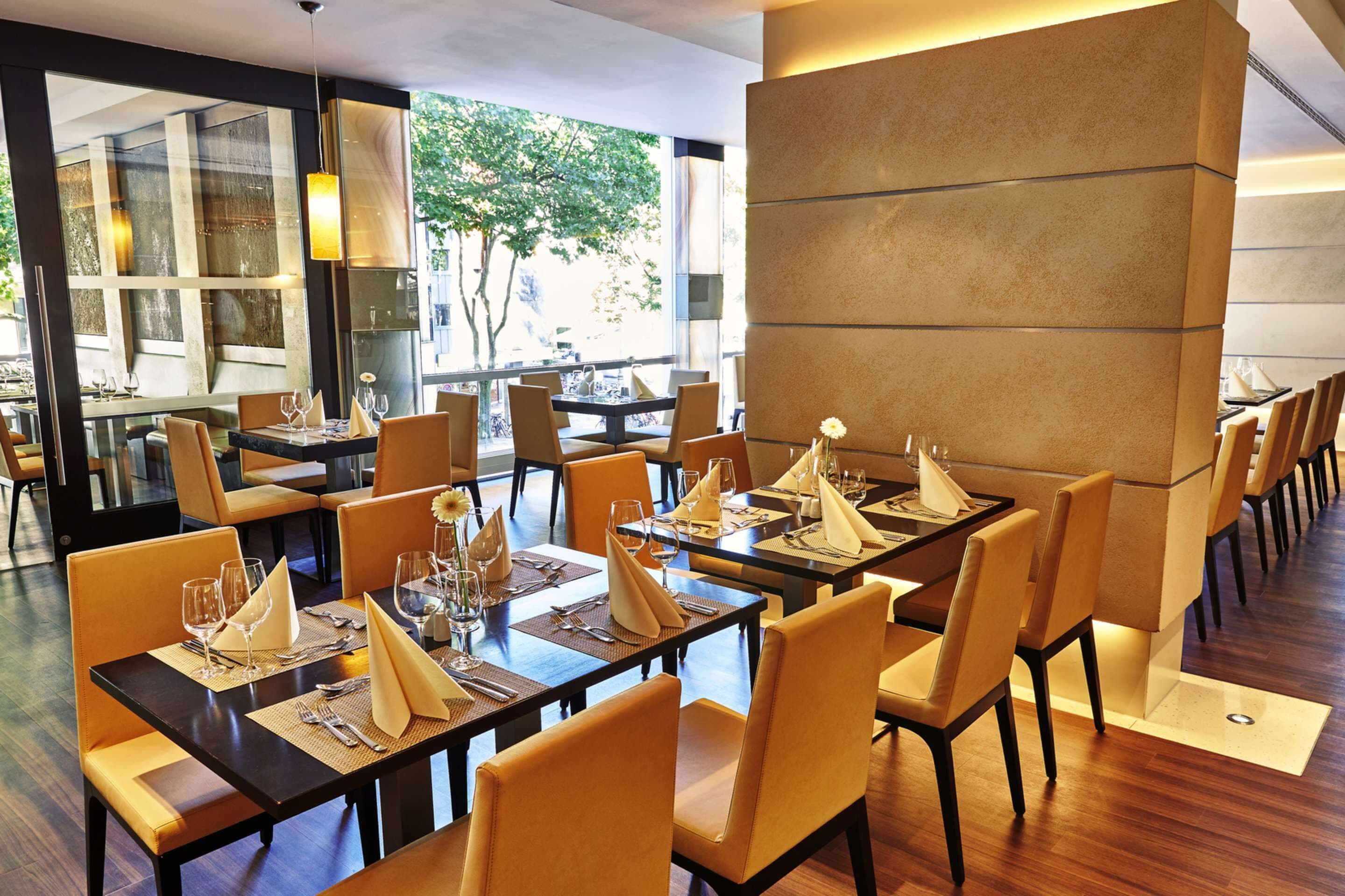 Un restaurant moderne avec de grandes tables, des chaises confortables et une vue sur l’extérieur.