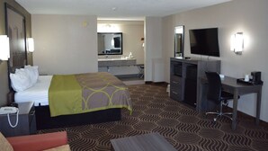 A hotel room with a bed, desk, chair, television, and a bathroom with a mirror and sink.