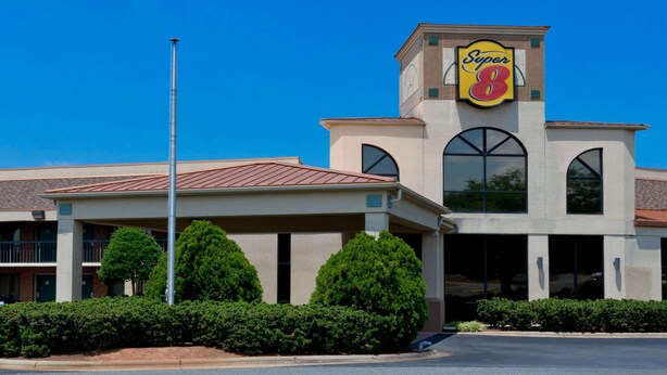 Un hotel Super 8 con un llamativo letrero de 'Super 8', una construcción de dos pisos y un estacionamiento.