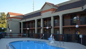 Un hotel con piscina, varios balcones y fachada de ladrillo.
