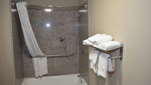 A bathroom with a shower, a bathtub, and a towel rack with folded towels.
