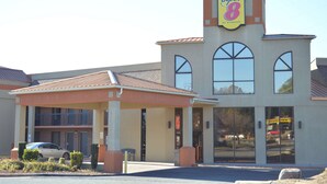 A Super 8 by Wyndham hotel with a covered entrance, a car parked outside, and a clear sky.