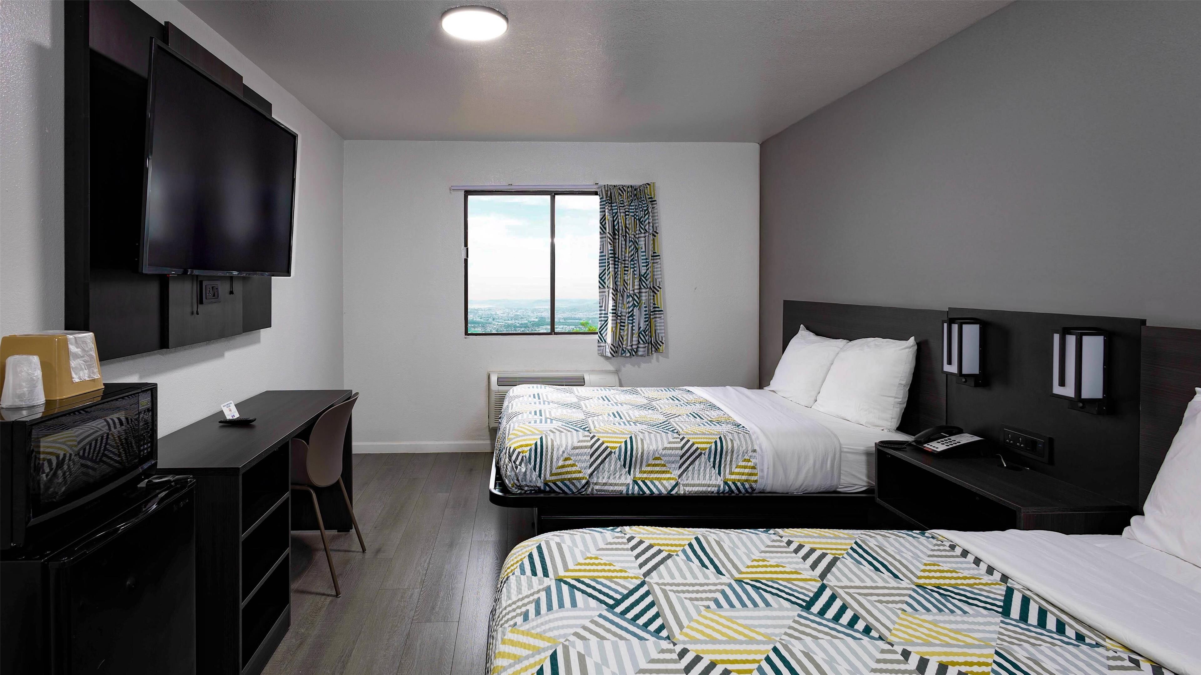 Een hotelkamer met twee bedden, een bureau, een televisie en een raam met uitzicht.