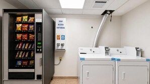 En automattankomat med snacks, en dispenser för tvål och blekmedel, och en tvättmaskin från Whirlpool.