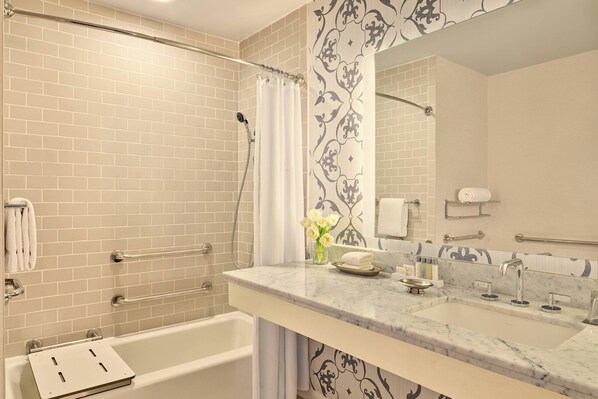A bathroom with a bathtub, a shower, a vanity with a sink, and a mirror.