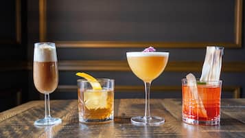 Vier verschiedene Cocktails auf einem Holztisch.