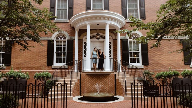 A brick building with a central entrance featuring a white porch and a fountain. - Morrison House Old Town Alexandria, Autograph Collection (Alexandria)