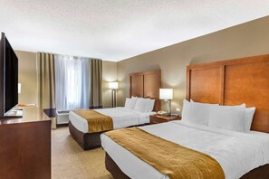 Une chambre d’hôtel avec deux lits, un bureau, une télévision et une lampe.
