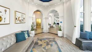 A spacious lobby with a high ceiling, a central seating area, and a view into the dining area. - Castle Hotel, Autograph Collection (Orlando)